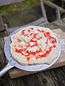 Frisch aus dem Ofen kommende Sauerteigpizza, auf einer Seite leicht angebrannt und mit Parmesan belegt
