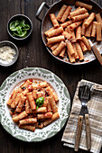 Portion of Italian pasta 'tortiglioni' with tomato sauce, on wooden table. View from above.