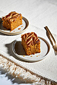 Pumpkin pie square with almond butter swirls on a neutral background with golden forks