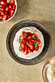 Strawberry and mint pavlova with cream on a grey serving dish
