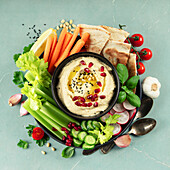 A colourful hummus platter with fresh vegetables, pita, pomegranate and herbs, perfect for menus, healthy eating concepts and food photography