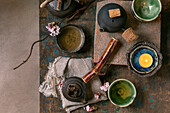Chinese tea ceremony. Three traditional handmade black ceramic teapots with wooden handles on a dark wooden table. Ceramic teacups and pink spring flowers, burning tea light. Tea ceramics. View from above
