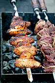 Close-up of spiced chicken and beef skewers on the charcoal grill. Smoked meat with spices during an outdoor barbecue. Perfect for a summer barbecue party.