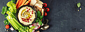 Eine schön angerichtete Hummus-Platte mit frischem Gemüse, Fladenbrot, Granatapfelkernen und Sesam. Perfekt für gesunde Ernährungskonzepte, Speisekarten, Blogs und Bannerdesigns.