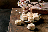 Traditional Asian dessert sweets Sesame cream sweets on ceramic plate. Rustic wooden table decorated with cherry blossom branches. Homemade rice flour pastry rolls.