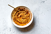 A bowl of mixed spices with a golden spoon on a textured surface.