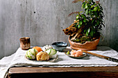 Temari sushi. Trendy sushi balls with salmon, avocado, cucumber and Japanese omelette on a wabi-sabi plate. Soy sauce, pickled ginger, ikebana on table with grey linen cloth. Grey textured background.
