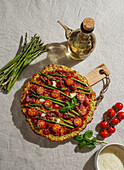 Freshly baked pizza with courgette crust, topped with cherry tomatoes, asparagus, spinach leaves and ricotta cheese.