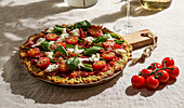 Freshly baked pizza with courgette crust, topped with cherry tomatoes, asparagus, spinach leaves and ricotta cheese.