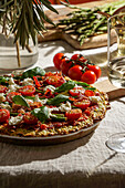 Freshly baked pizza with courgette crust, topped with cherry tomatoes, asparagus, spinach leaves and ricotta cheese.