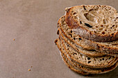 Close-up of stack of freshly sliced sourdough bread with crispy crust porous texture on beige background. Rustic homemade bread with air bubbles.