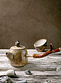 Original handmade ceramic teapot with wooden handle and cups for traditional Chinese tea drinking on an old wooden table. Decorative pebbles all round. Space for copying