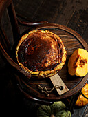 Basque pumpkin cheesecake on a dark vintage chair, rustic and atmospheric autumn aesthetics