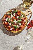 Freshly baked pizza with courgette crust, topped with cherry tomatoes, asparagus, spinach leaves and ricotta cheese.