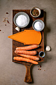 Korean and Asian cuisine. Ingredients for preparing a vegetable salad from marinated carrots. Raw carrots, spices, grater in a row. Mocha mousse colour background. Healthy cooking. Top view, room