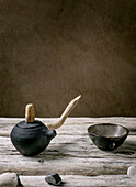 Original handmade ceramic teapot with wooden handle and cups for traditional Chinese tea drinking on an old wooden table. Decorative pebbles all round. Copy space