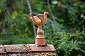 Clay figure of a bird on a tiled roof in the garden