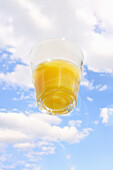 Glass of orange juice in front of the sky