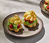 Mini cream puffs with matcha cream and raspberries