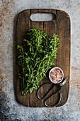 Wild mint with pink salt and herb scissors on a wooden board