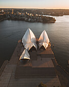 Luftaufnahme des Opernhauses von Sydney bei Sonnenaufgang mit lebhaften Reflexionen auf dem Wasser, Sydney, Australien.