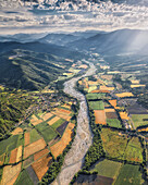 Aerial view of dry river with lavender fields around with mountains in background in Bras-d'Asse, Alpes-de-Haute-Provence, France.