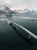 Aerial view of iconic Fredvang Bridges and snowy mountains, Lofoten Islands, Northern Norway in the Arctic Circle