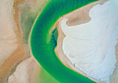Aerial drone view of a creek running in the Noosa North Shore sandbank at sunset on the Sunshine Coast, in Queensland Australia. The green colour of the water comes from sediments brought in by tides.