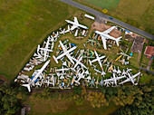 Aerial view of abandoned airplanes and helicopters in a rusty graveyard surrounded by trees and fields, Zruc Senec, Czech Republic.