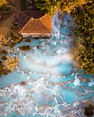 Aerial view of natural thermal spring pool with steam at sunrise, Terme di Saturnia, Italy.