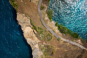 aerial view of woman laying in dress on path at Broken Beach in Nusa Penida, Indonesia.