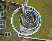 Luftaufnahme einer kreisförmigen Struktur und eines Parkplatzes mit spiralförmigem Weg und Grünflächen, Camoes Car Park, Guimaraes, Portugal