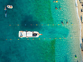 Aerial view of passenger boat entering buoy line on beach coast of Agios Nikitas, Greece.