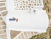 Aerial view woman lying on the roof on Santorini traditional house, Greece.