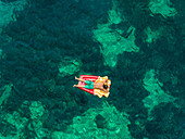 Aerial view of man floating in inflatable on Katomeri beach, Greece.