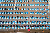 Aerial view of colorful beach umbrellas arranged on sandy shore with a scenic Mediterranean sea, Positano, Italy.