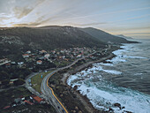 Aerial view of Cabo Silleiro with lighthouse and winding coastal road, Oia, Spain.