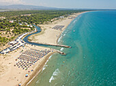 Aerial view of coastline with river entering sea with straw parasols on Achaia, Greece.