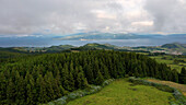 Luftaufnahme von üppig grünen Hügeln und ruhigem Meer, Faial, Azoren, Portugal.