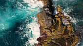 Luftaufnahme der zerklüfteten Küste mit krachenden Wellen und strahlend blauem Meer, Horta, Azoren, Portugal.