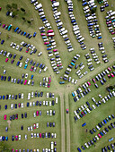 Aerial view of a parking lot filled with parked cars surrounded by green fields, West Firle, United Kingdom.