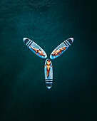 Aerial view of a female surfer paddling on a blue ocean with a surfboard, Primorje-Gorski Kotar, Croatia.