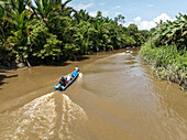 Aerial view of a serene tropical river surrounded by lush jungle and traditional boats, Siberut Island, Indonesia.