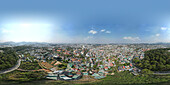 Luftaufnahme einer pulsierenden Stadtlandschaft mit schönen Gebäuden und üppigem Grün, umgeben von Hügeln, Da Lat, Vietnam.