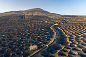 Aerial view of a woman walking among volcano holes formation at Timanfaya national park, Lanzarote Island, Canary Islands, Spain.