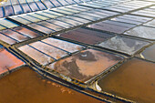 Aerial view of the patterns and colors of salt evaporation ponds during sunrise time in Aveiro, Portugal