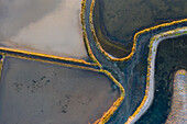 Aerial view of the patterns and colors of salt evaporation ponds during sunrise time in Aveiro, Portugal