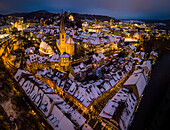 Aerial view of snow-capped roofs of historic town of Baden, Switzerland, with colorful christmas lights lighting the streets