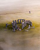 Luftaufnahme der alten megalithischen Stonehenge-Struktur, umgeben von Feldern, während der goldenen Stunde, Salisbury Plain, Vereinigtes Königreich.