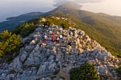 Luftaufnahme einer Gruppe, die auf dem Gipfel eines Berges Yoga praktiziert, Veli Lošinj, Kroatien.
